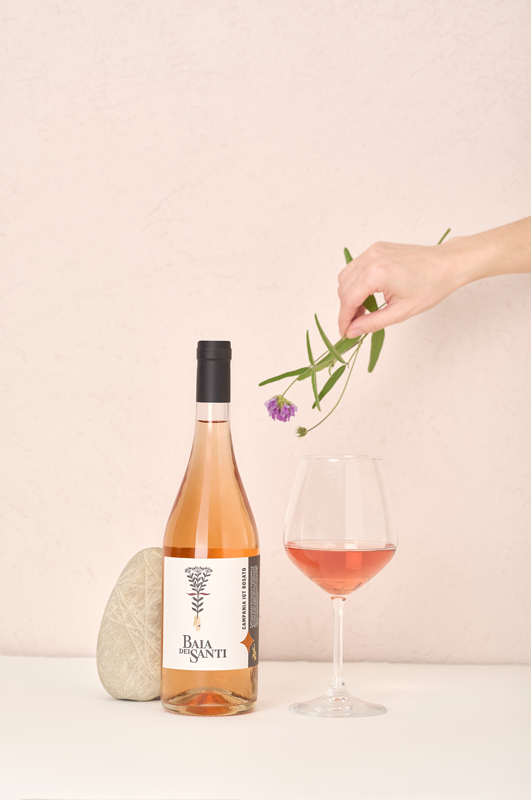 Bottiglia del vino Campania IGT Rosato di Baia DeiSanti con mano che regge un fiore